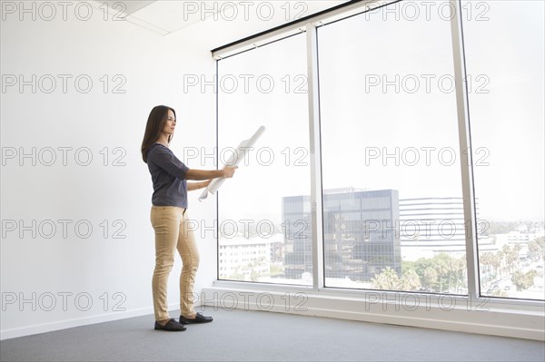 Woman reading blueprints in empty office