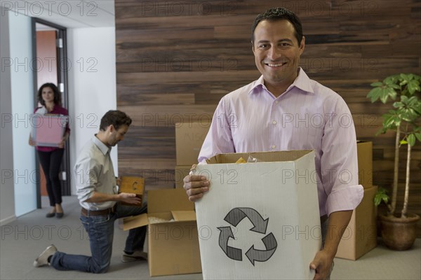 Hispanic businessman carrying cardboard box in office