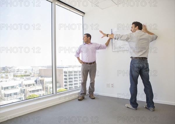 Hispanic businessmen examining blueprints in office