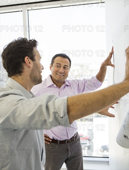 Hispanic businessmen examining blueprints in office