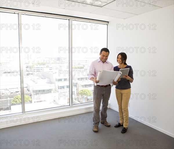 Business people examining blueprints in office