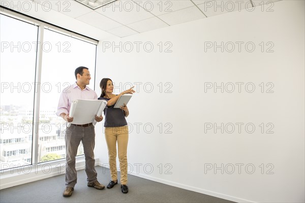 Business people examining blueprints in office