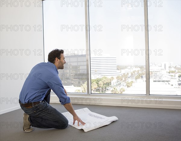 Hispanic businessman examining blueprints in office