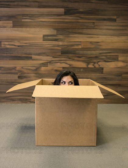 Mixed race woman hiding in cardboard box