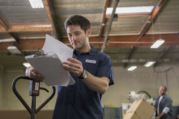 Worker reading clipboard in warehouse