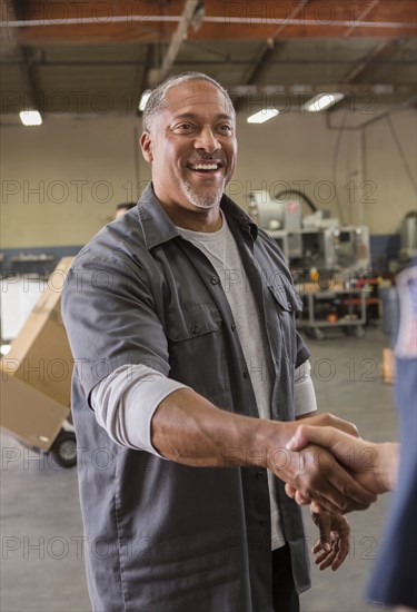 Workers shaking hands in warehouse