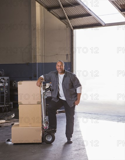 Worker with boxes on hand truck in warehouse