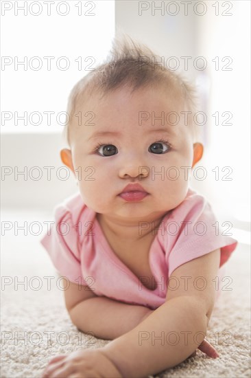 Mixed race baby girl laying on carpet