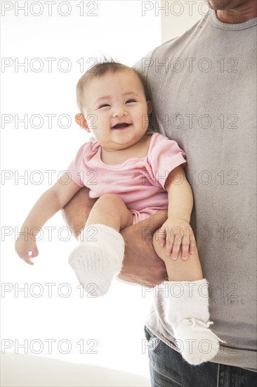 Father carrying laughing baby girl