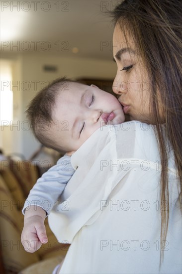 Mother kissing sleeping baby girl