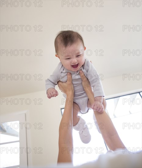 Mother holding baby girl overhead