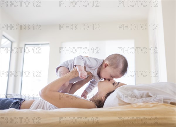 Mother playing with baby girl on bed