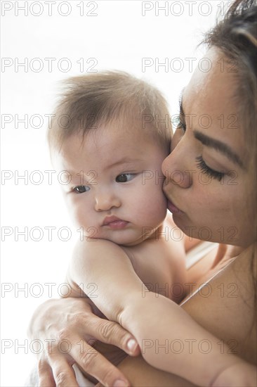 Mother kissing baby girl's cheek