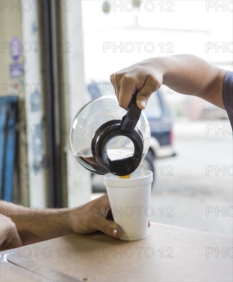 Workers pouring cup of coffee in warehouse