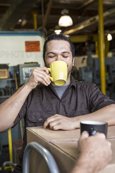 Worker drinking coffee in warehouse