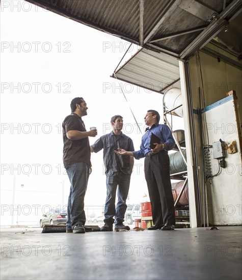 Manager and workers talking at warehouse loading dock