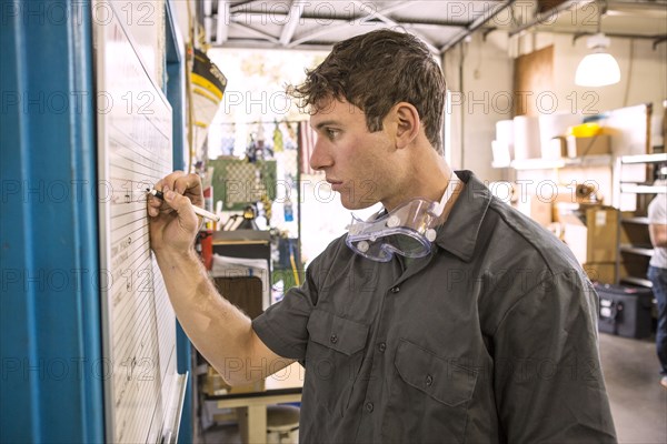 Caucasian worker writing on whiteboard in warehouse