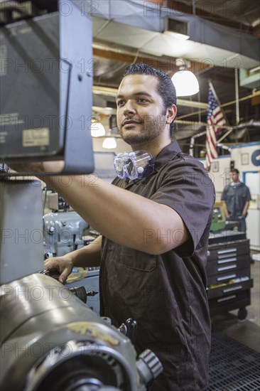 Hispanic worker operating machinery in factory