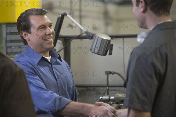 Worker and manager shaking hands in warehouse