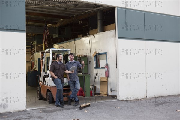 Workers using digital tablet at warehouse loading dock