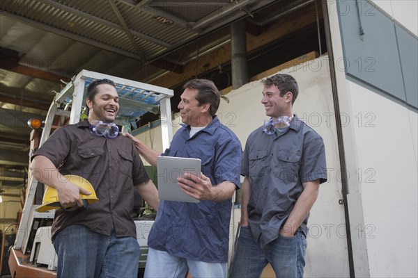 Workers using digital tablet at warehouse loading dock