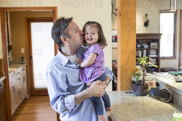 Father kissing daughter in kitchen