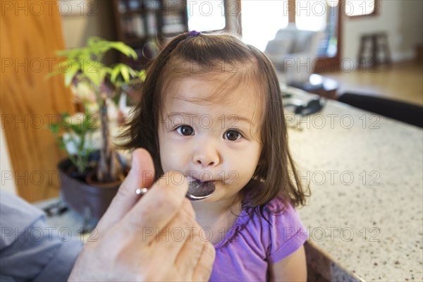 Father feeding daughter in kitchen