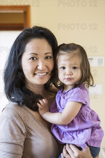 Mother holding daughter in kitchen