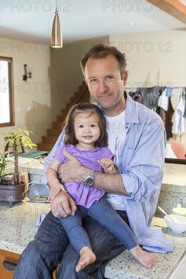 Father holding daughter in kitchen