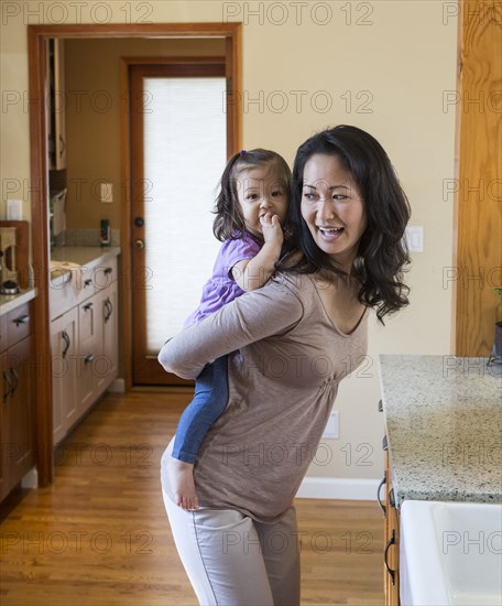 Mother holding daughter in kitchen