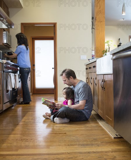 Father reading to daughter in kitchen