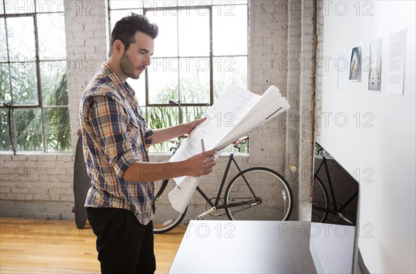 Caucasian architect reading blueprints in office