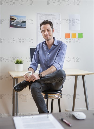 Caucasian architect drinking coffee in office