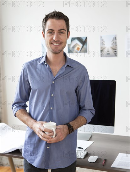 Caucasian architect drinking coffee in office