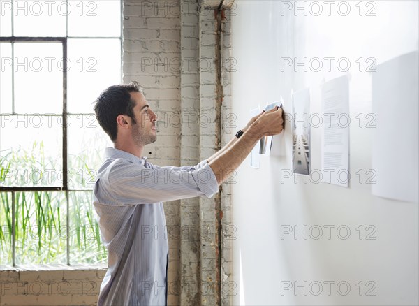 Caucasian architect hanging photos in office
