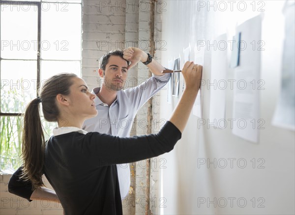 Caucasian architects drawing on photos in office