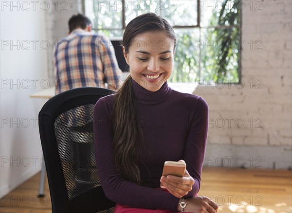 Mixed race architect using cell phone in office