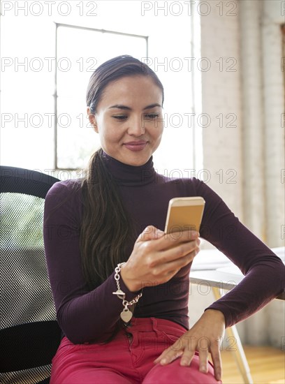 Mixed race architect using cell phone in office