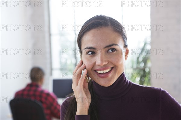 Mixed race architect talking on cell phone in office