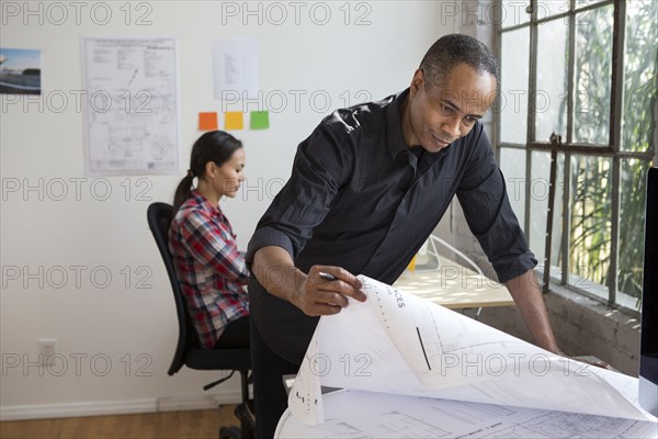 African American architect designing blueprints in office