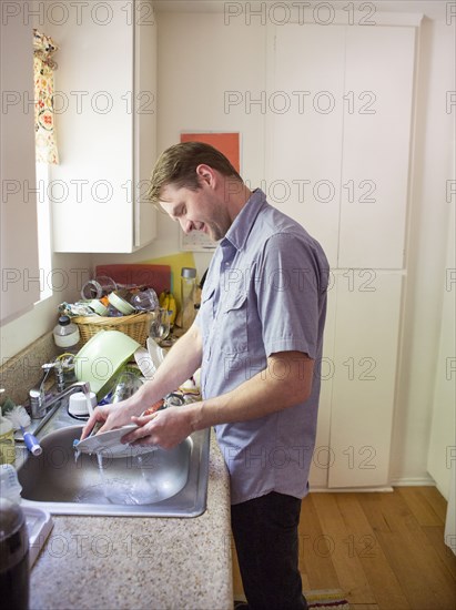 Caucasian man washing dishes in kitchen