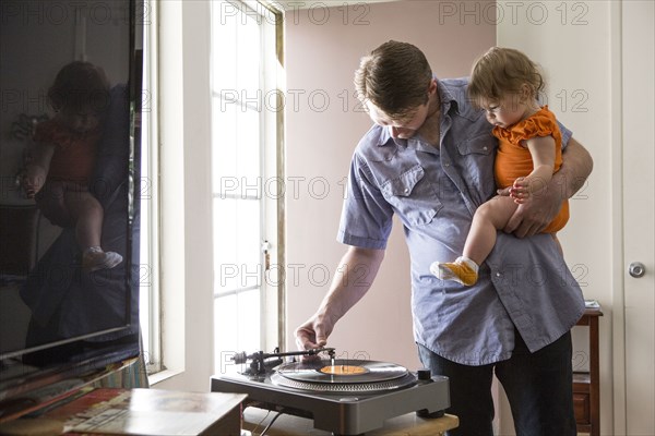 Caucasian father playing records with daughter