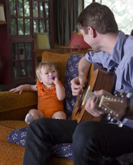 Caucasian father playing guitar for daughter