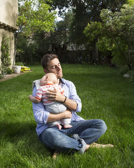 Caucasian father holding baby in backyard