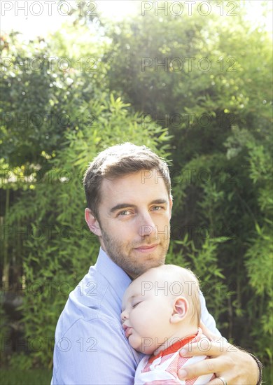 Caucasian father holding baby in backyard