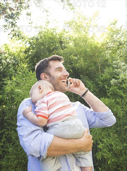 Caucasian father on cell phone holding baby