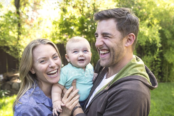 Caucasian couple holding baby in backyard