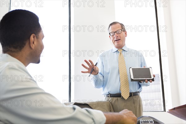 Businessman showing digital tablet to colleagues in meeting