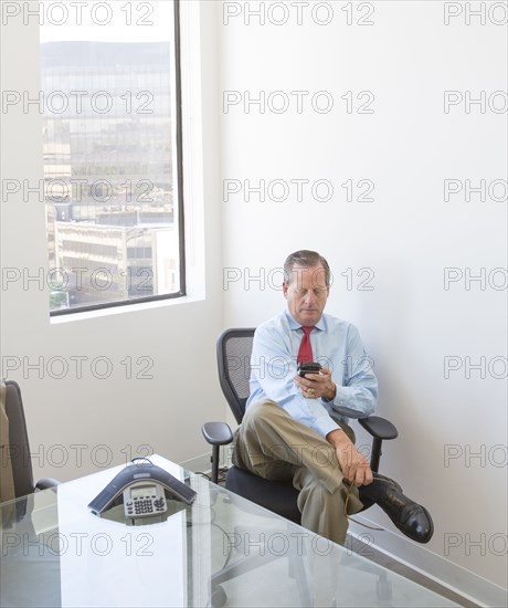 Caucasian businessman using cell phone at desk in office