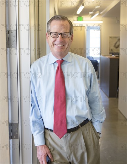 Caucasian businessman smiling in office hallway